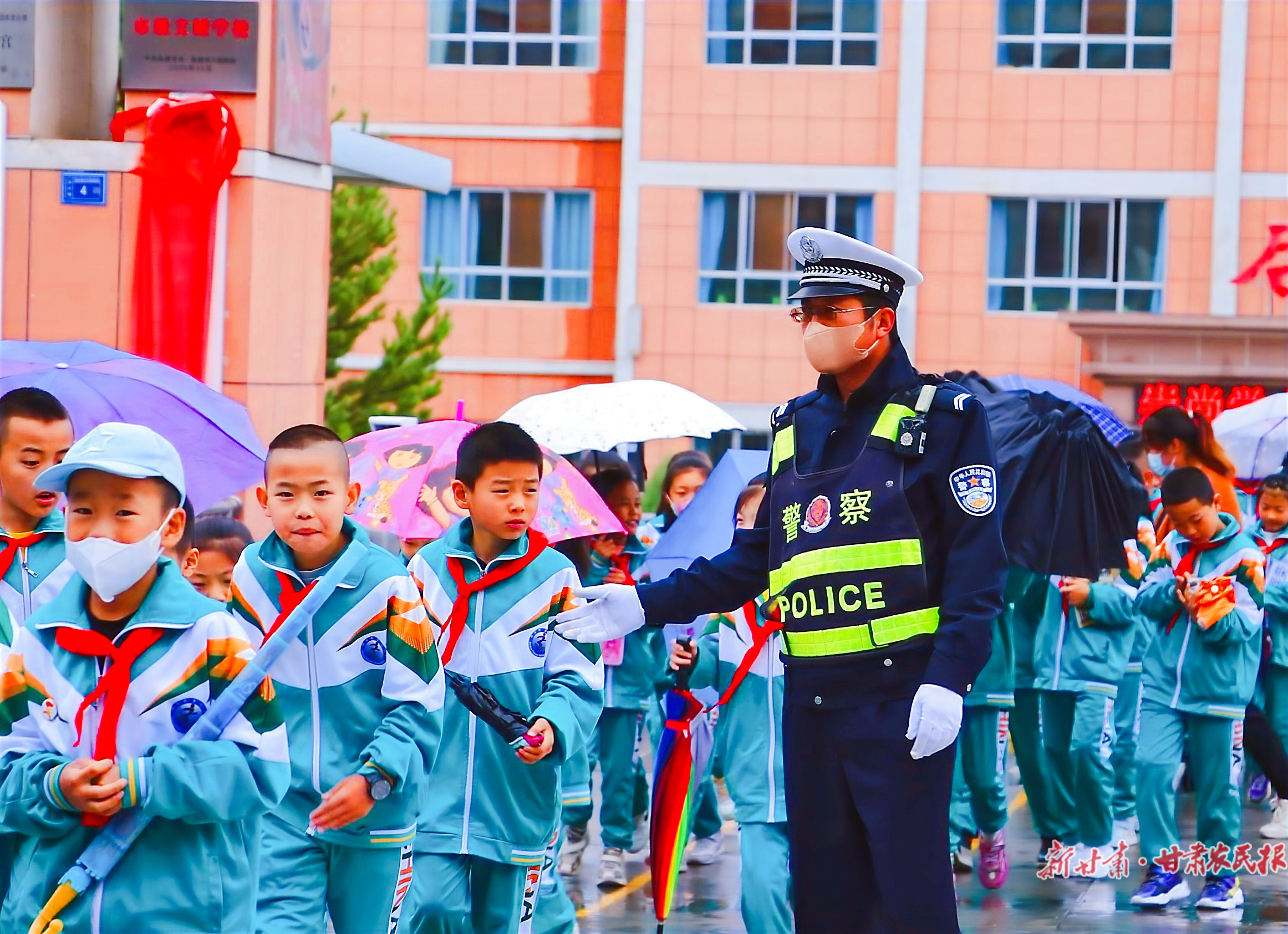 执勤交警在民乐县金山小学门口护送孩子们过马路。王超摄